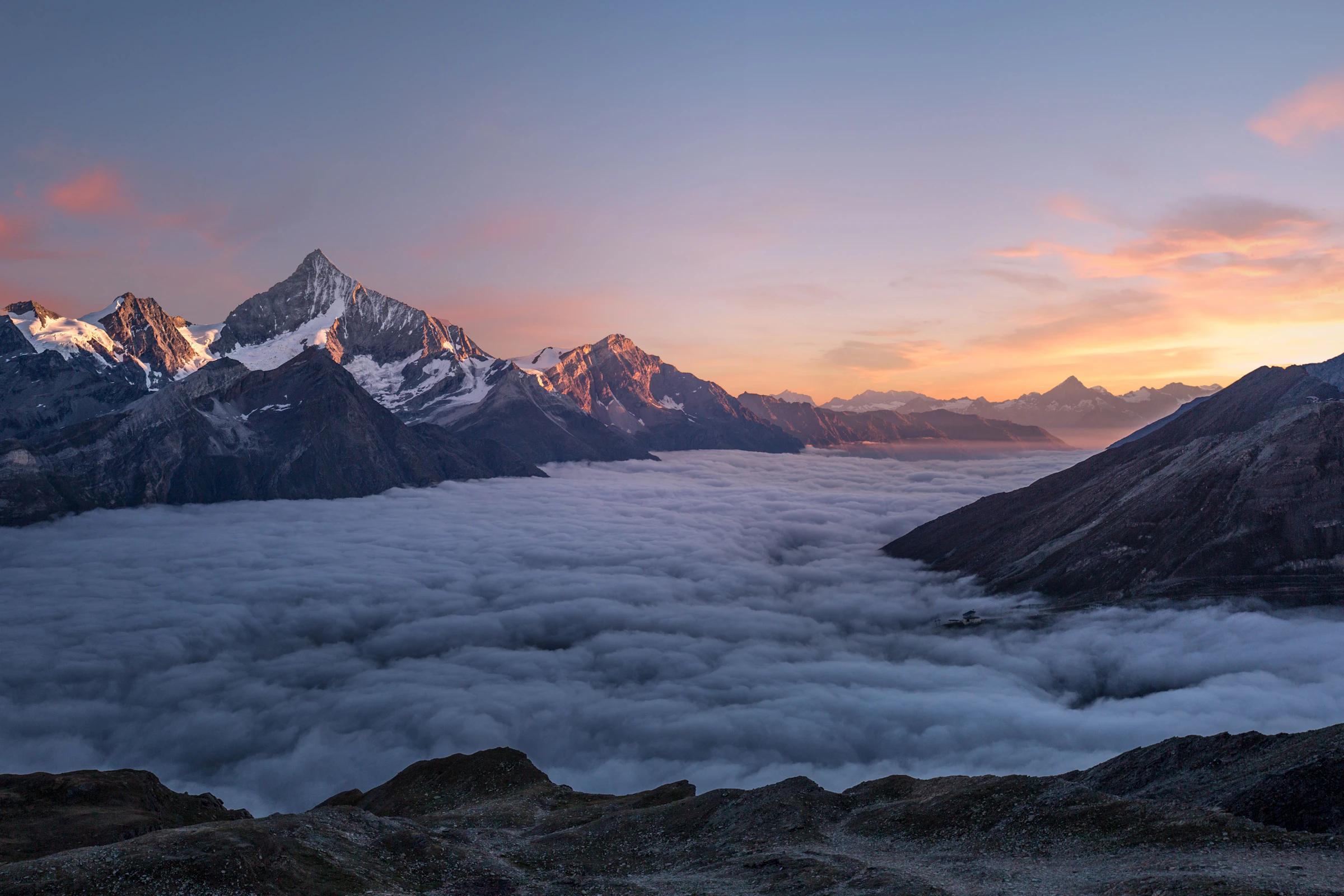 Sea of clouds at dawn below a mountain ridge